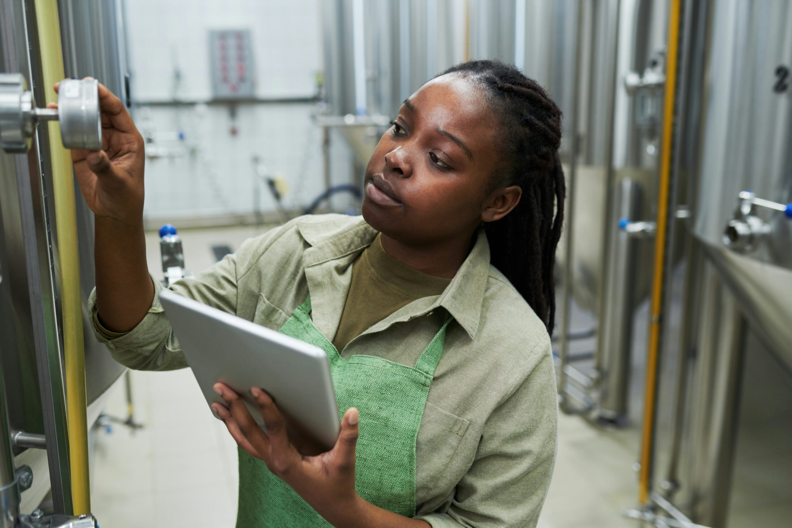 Technician adjusting equipment in a soap manufacturing facility while holding a tablet.