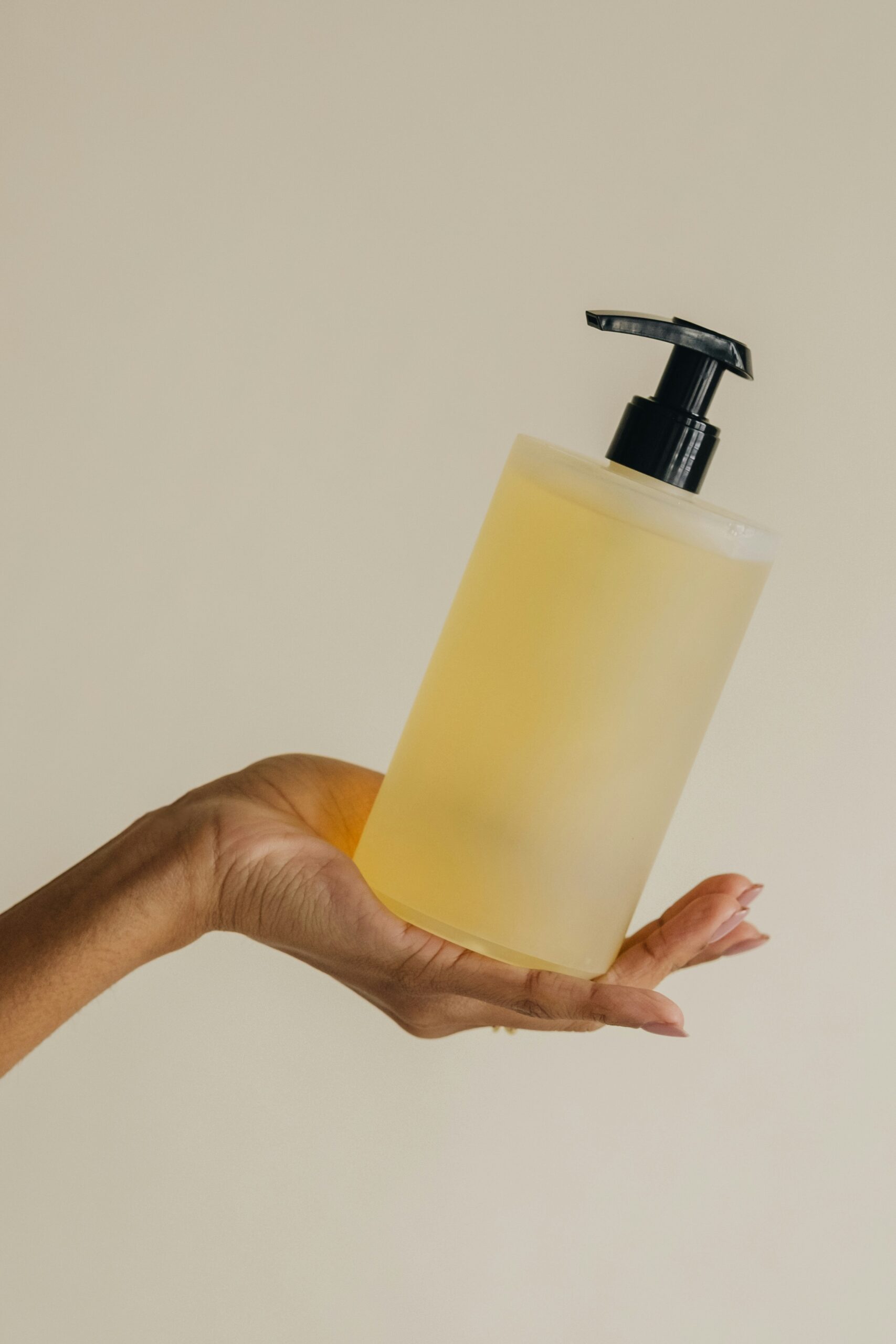 Custom liquid soap in minimal packaging – Vanguard Soap A clear bottle of custom liquid soap with a black pump, held in an open hand